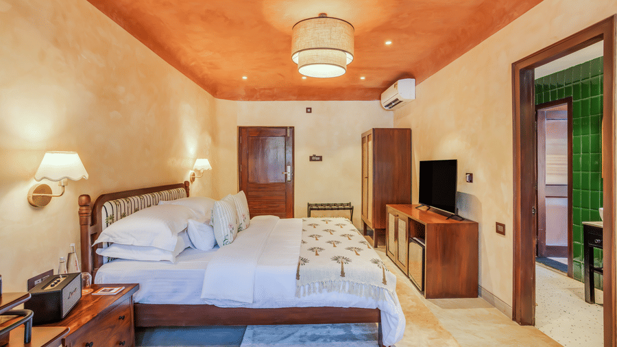 Inviting bedroom at Unseen Boutique Hotel with reddish?orange ceiling, plush bed, and rustic wooden furniture.