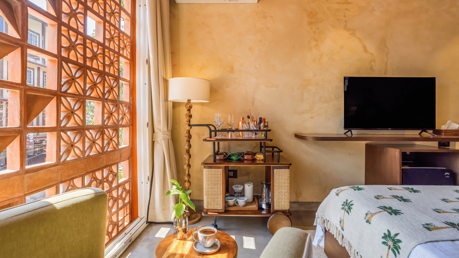 Bedroom at Unseen Boutique Hotel with patterned bedspread, wooden furniture, bedside lamps, and wall?mounted TV.