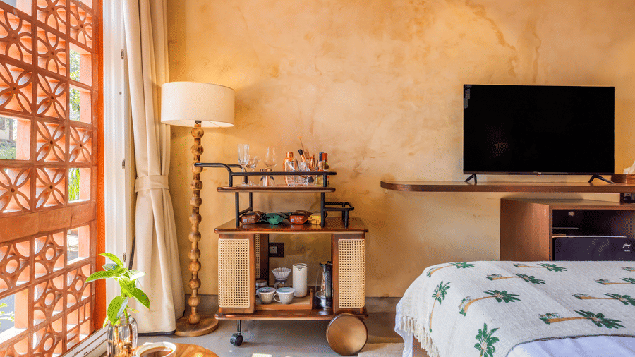 Bedroom at Unseen Boutique Hotel with patterned bedspread, wooden furniture, bedside lamps, and wall?mounted TV.