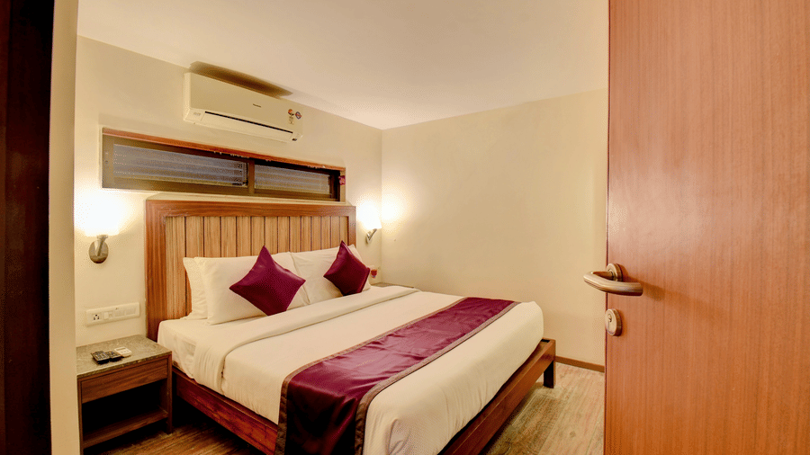 Cozy bedroom with wooden headboard and elegant purple accents at VITS Lonavala.
