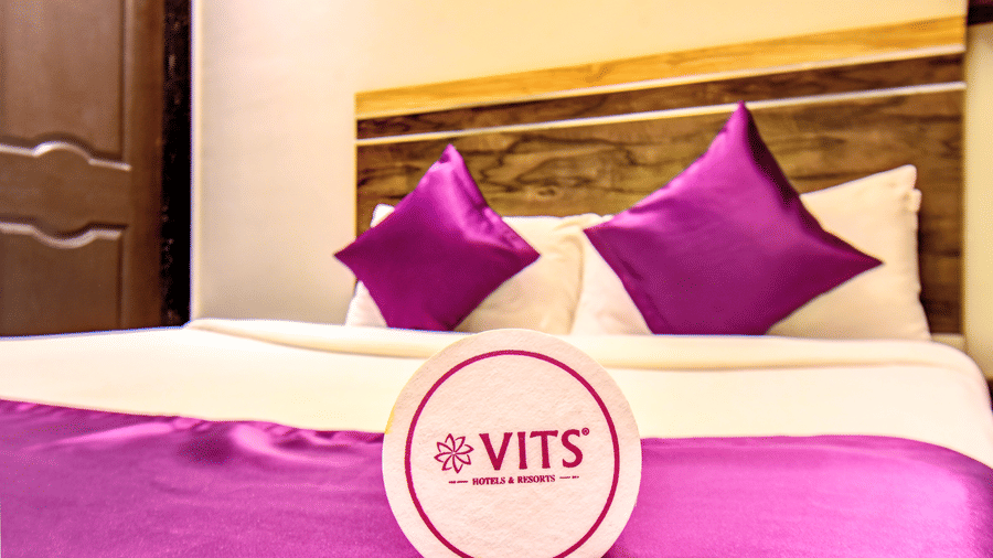 Deluxe Room king bed with purple linen and VITS Hotels and Resorts logo coaster at VITS Select Kharadi Pune