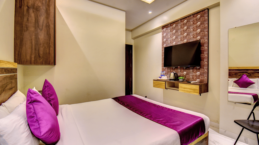 Deluxe Room wide view with king bed, purple linen, wall-mounted TV and ceiling fan at VITS Select Kharadi Pune