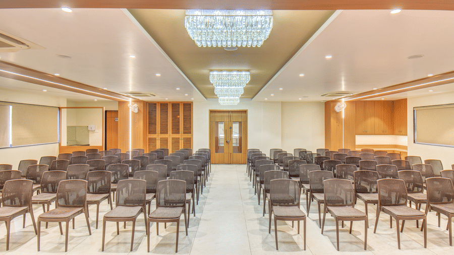 Ballroom at VITS Select Nashik Hotels & Resorts featuring chairs lined up under warm lighting and a door in the background