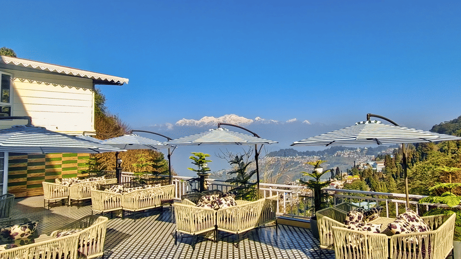 Sunny outdoor restaurant terrace with mountain views and white patio umbrellas | Voyage Rodhi Resort