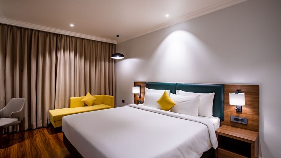 a double bed with led lights on and a sofa on the side inside one of the rooms - Wedlock Greens Hotel Resorts Dhanbad