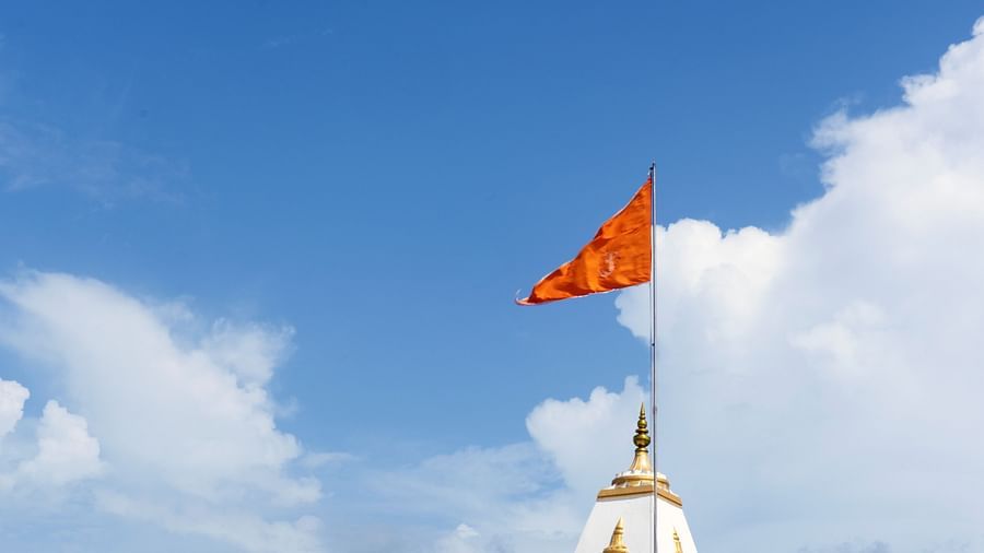 a red flag on top of a white temple with white clouds over the blue sky