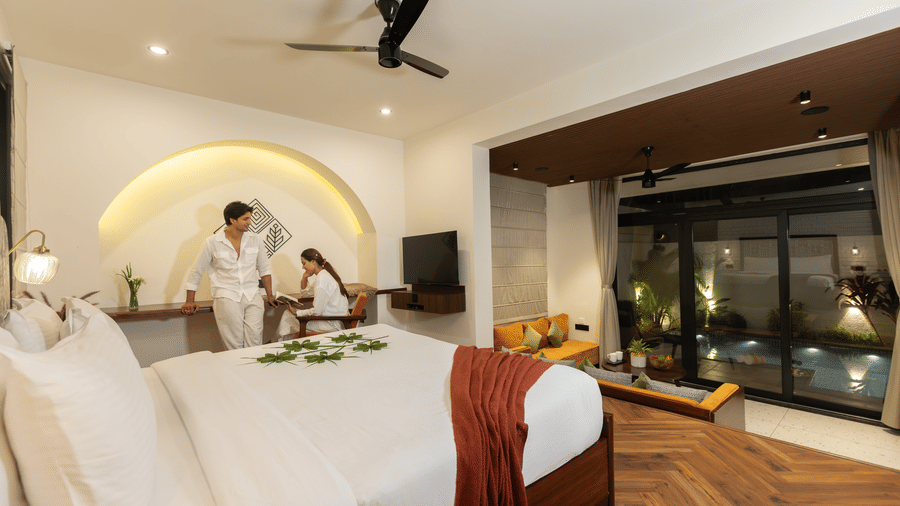 bedroom with a large bed featuring a person in a white robe, modern cabinetry, and sleek decor at The Golden Tusk, Jim Corbett