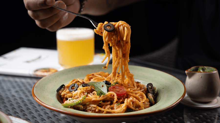 spaghetti in a bowl with a glass of orange juice and a fork at  at The Golden Tusk, Jim Corbett