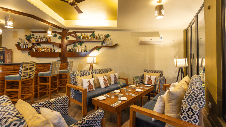 lounge area with unique tree-shaped decor, tables, and cushioned seating  at The Golden Tusk, Jim Corbett