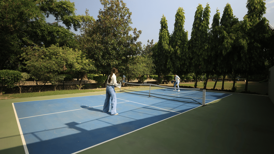 People playing pickleball on a outdoor court enclosed by a fence at The Golden Tusk, Jim Corbett