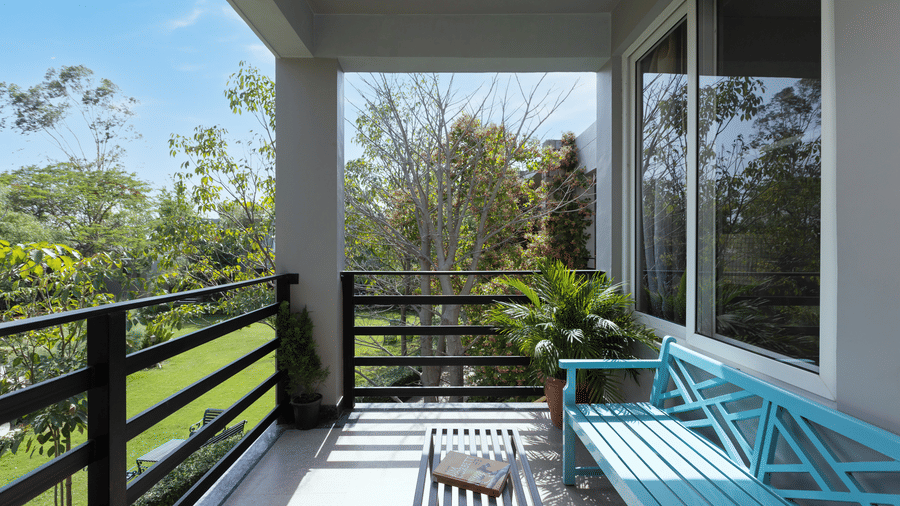 Pool View Suite balcony with a bench, chairs, and views of trees and sky at The Golden Tusk, Jim Corbett