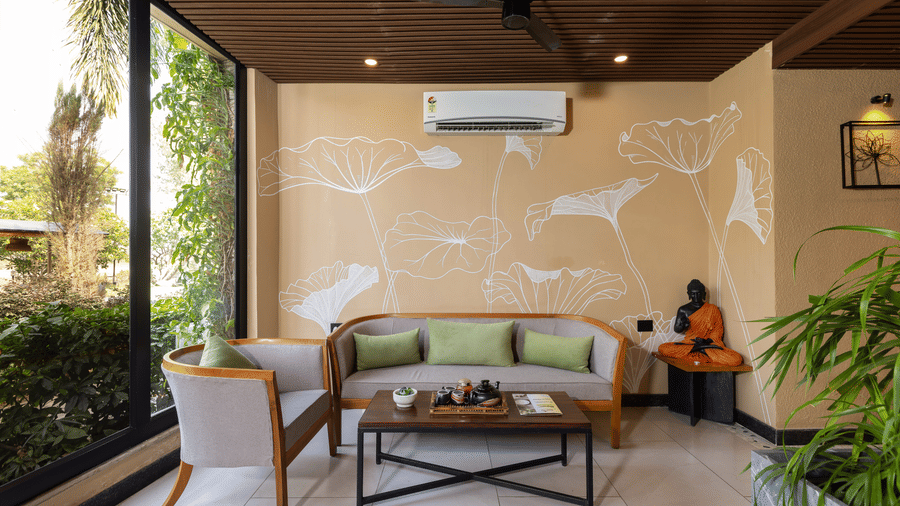 A brightly lit spa area featuring a grey sofa, a wooden coffee table, a single armchair, and walls decorated at The Golden Tusk, Jim Corbett
