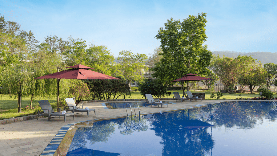 A large outdoor swimming pool with water and a red umbrella 