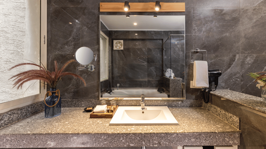 Villa Grande's contemporary bathroom vanity area with a sink, mirror, and dark textured walls at The Golden Tusk, Jim Corbett
