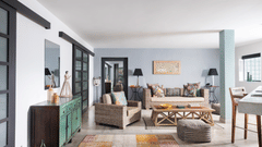 A bright indoor space at Owl and the Pussycat Hotel in Galle featuring a sofa with cushions, a low wooden coffee table, and a long sideboard with multiple cabinet doors under a large wall mirror.