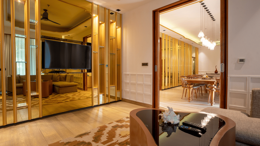 A stylishly decorated hotel room with a large bed and a prominent gold-toned, mirrored wall that reflects the room's elegant and contemporary design.