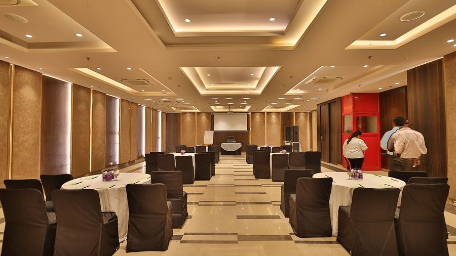 A spacious banquet hall with multiple tables covered in dark cloths, set up for a formal event.