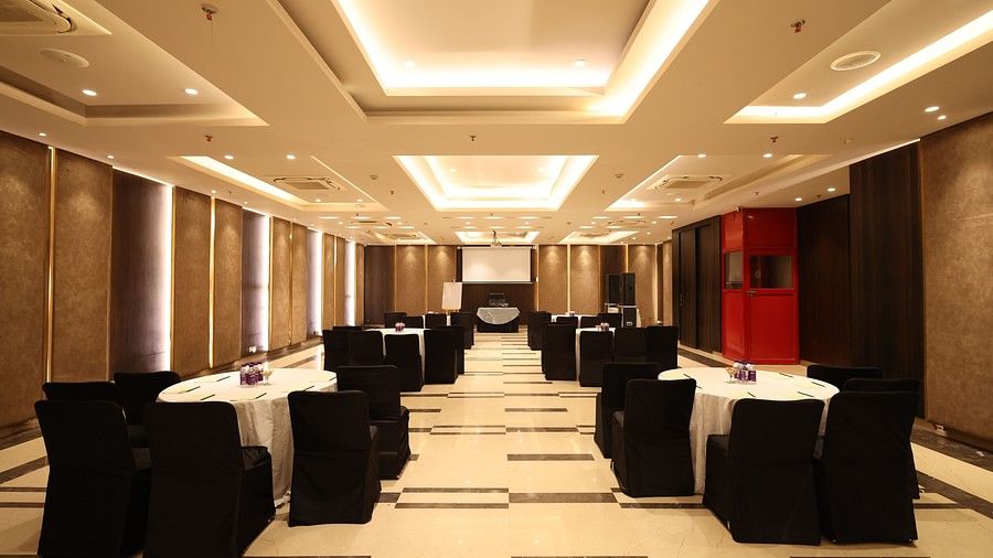A large banquet or conference hall with multiple tables and chairs, elegantly decorated for an event.