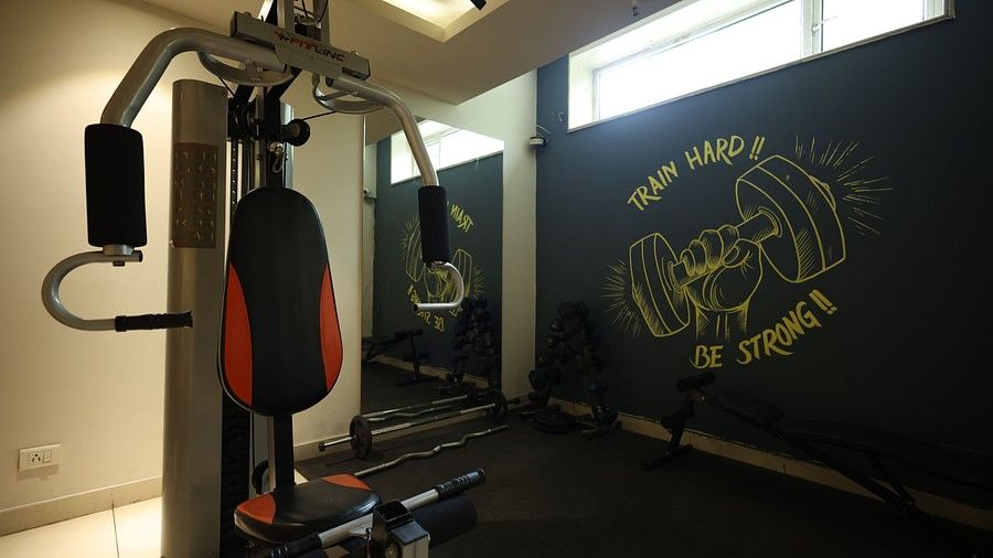 A dynamic hotel gym with a weight machine, boxing gloves, and a black wall with a motivational chalk drawing.