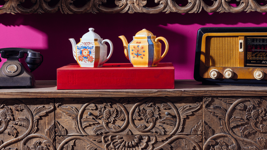 A decorative shelf with 2 ceramic jars and a vintage radio placed above a carved wooden panel at Owl and the Pussycat Hotel in Galle.