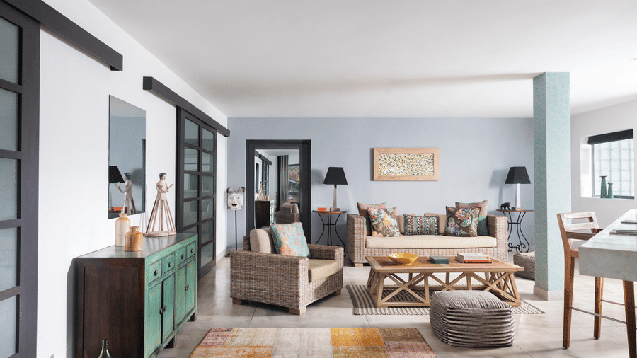 A bright indoor space at Owl and the Pussycat Hotel in Galle featuring a sofa with cushions, a low wooden coffee table, and a long sideboard with multiple cabinet doors under a large wall mirror.