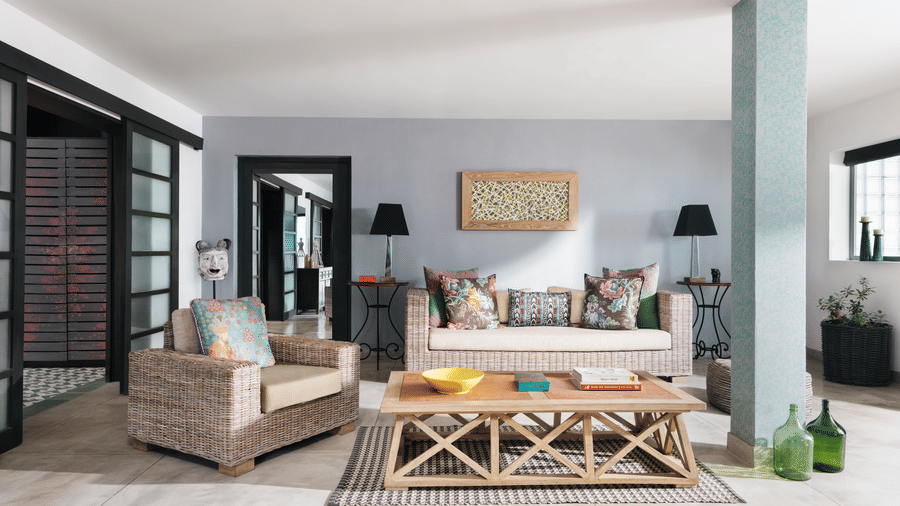 A room at Owl and the Pussycat Hotel in Galle featuring a sofa and an armchair arranged around a wooden coffee table, with sliding glass doors leading to other interior spaces.