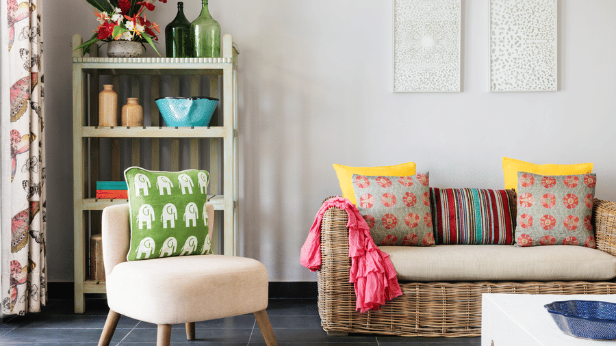 A living space at Owl and the Pussycat Hotel in Galle with a sofa, accent chair, shelving unit, cushions, and decorative objects.