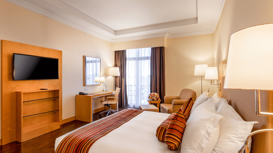 An overview of a room with a double bed with a tv wall mounted opposite it - Ramada by Wyndham Addis, Addis Ababa.