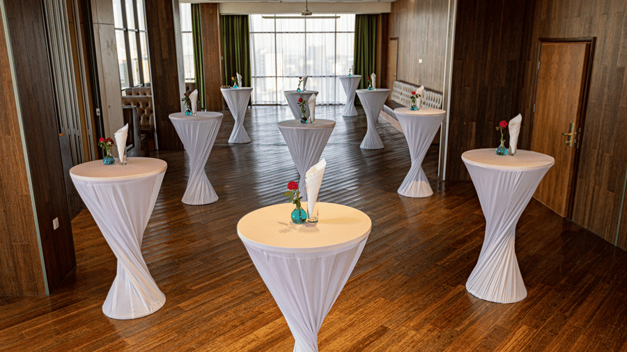An overview of a event space with many round tables having a vase on it inside - Ramada by Wyndham Addis, Addis Ababa.