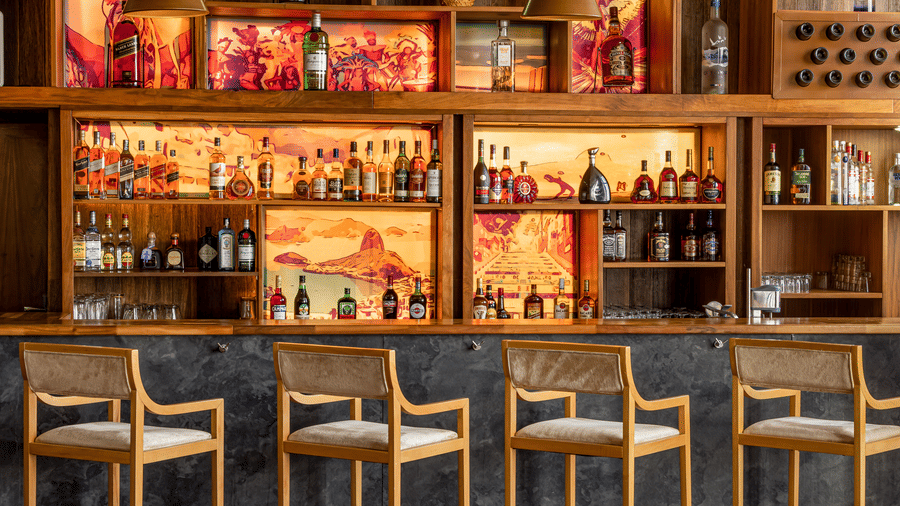 An overview of the bar counter and the showcase behind it containing many bottles of drinks inside FOGO NO CHÃO - Ramada by Wyndham Addis, Addis Ababa