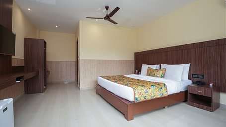 Premium Room with a large bed, wooden furniture and storage, mini fridge, and wall-mounted TV at Summit Green Lake Tea Resort & Spa, Kaziranga
