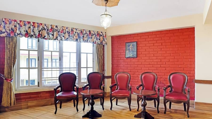 A front view of chairs placed in a hall that has glass windows and a handing roof light | Summit Newa Regency & Spa, Pelling
