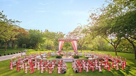 An elegant setting of chairs facing towards the stage in a lawn on a sunny day at Essentia Luxury Resort & Spa, Udaipur. 