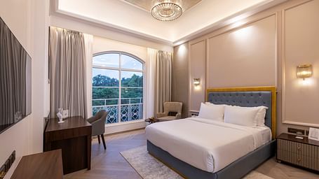 Corner view of the Deluxe Room featuring a double bed and a chandelier hanging from the ceiling right above it at Imperial Goa.