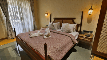 A comfortable king size bed decorated with swan-shaped towel art and soft ambient lighting - Tathastu Chavri Resort, Jawai