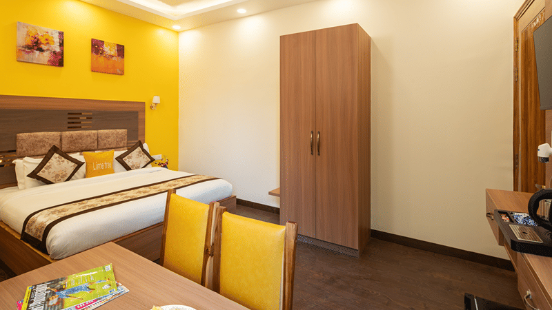 Deluxe hotel bedroom with a work desk, wardrobe, and comfortable queen bed.