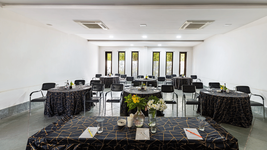An indoor event space arranged with several circular tables for a meeting | Anandam Jungle Retreat Resort, Udaipur