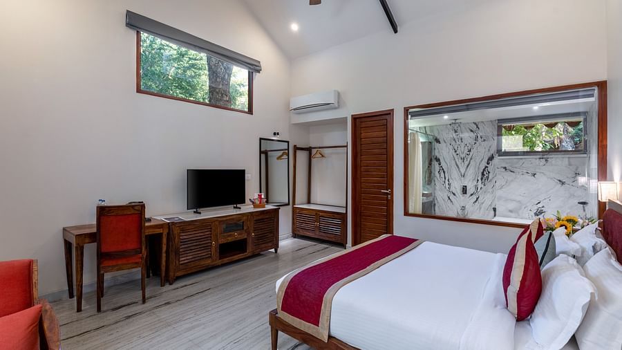 corner view image of the luxury bathtub villa featuring a king size bed along with the glass partition separating the bathroom from the room at aranya vilas in udaipur