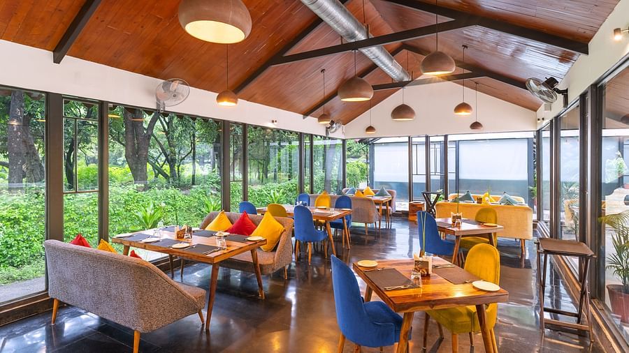 image of the kalptaru restaurant from a corner featuring lush greenery from the glass partition at aranya vilas in udaipur