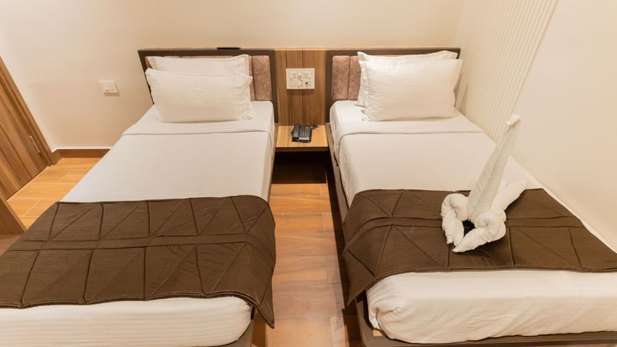Neat twin beds with towel swan decoration and a relaxing ambience at Beestay Hotels, Rajahmundry.