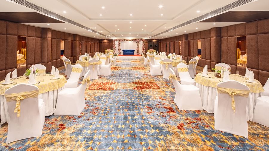 An image of a banquet hall with several chairs and table sets spread out - Brij Eternity, Vrindavan