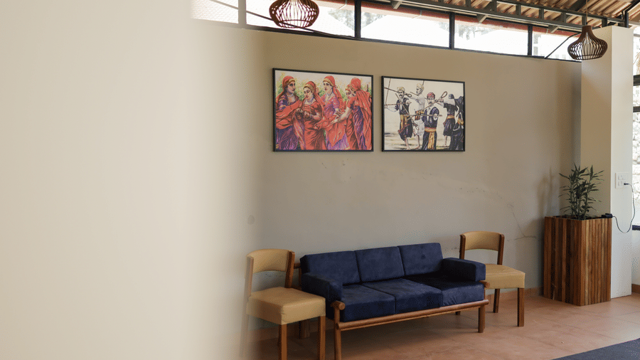 Minimalist reception lounge with a blue upholstered sofa, wooden chairs, and framed artwork on grey walls.