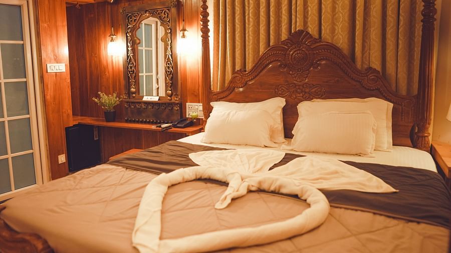 full view image of the comfortable king size bed with a huge wooden headboard at the far end of the bed