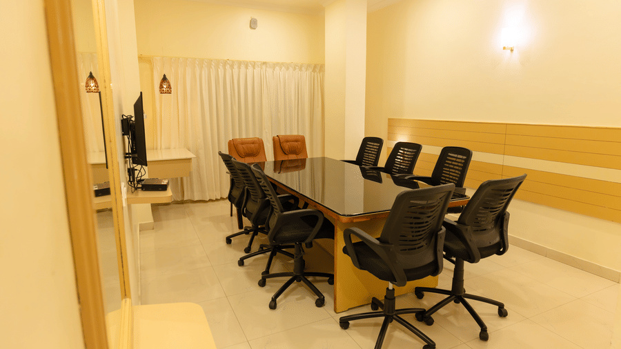 Boardroom at DSF Grand Plaza, Tuticorin with a glass-top table, mesh office chairs, a wall-mounted television, a mirror, and a striped wooden accent wall.