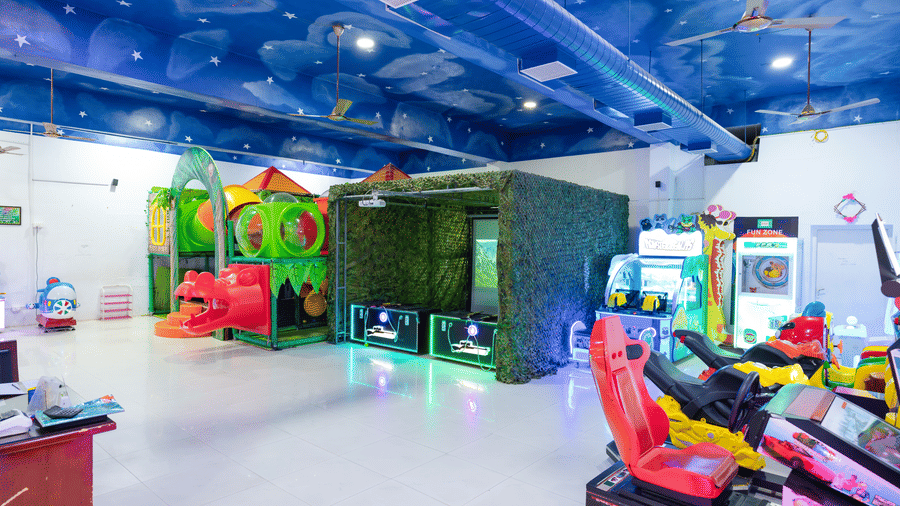 Full view of the DSF Fun Zone at DSF Grand Plaza, Tuticorin with a jungle-themed play structure, a camouflage-covered gaming booth, racing simulator seats, and a star-painted ceiling.