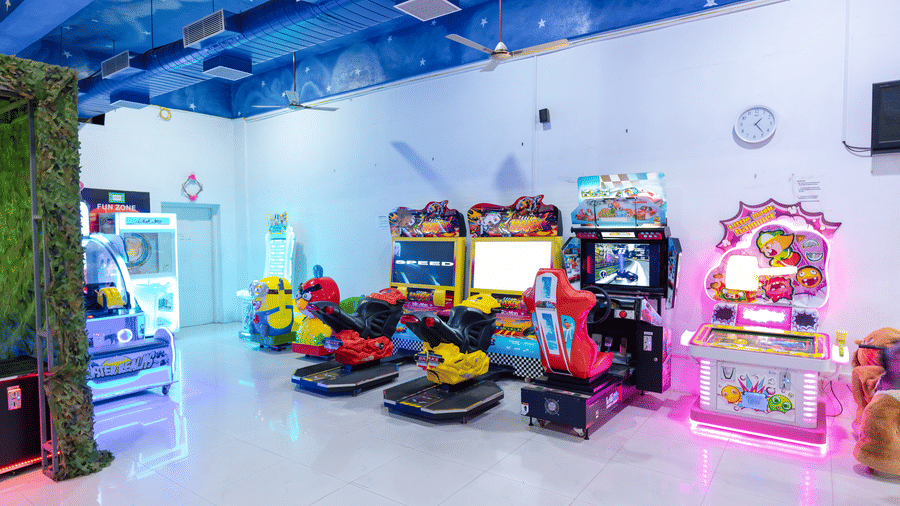 DSF Fun Zone gaming arcade at DSF Grand Plaza, Tuticorin with driving simulator machines, motorbike ride games, and pinball and claw machines under a star-painted ceiling.