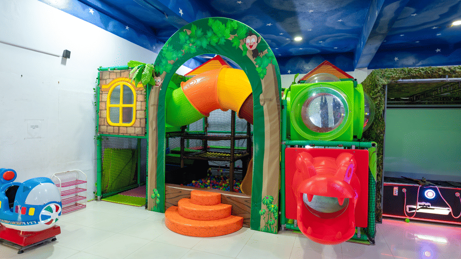 Indoor play area at DSF Grand Plaza, Tuticorin with a jungle-themed climbing structure, a tube slide, a ball pit, and an air hockey table under a star-painted ceiling.