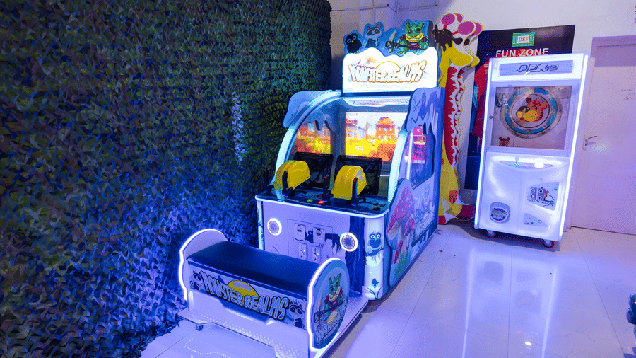 Monster Realms shooting arcade game and a claw machine at the DSF Fun Zone, DSF Grand Plaza, Tuticorin, against an artificial green foliage wall.