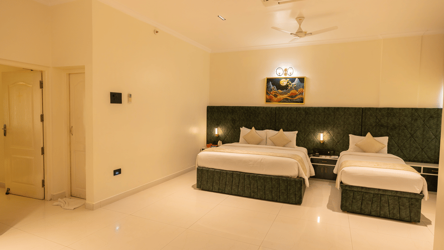 Spacious guest room at DSF Grand Plaza, Tuticorin with a double bed and single bed, green headboards, ceiling fan, cassette air conditioner, and wardrobe.
