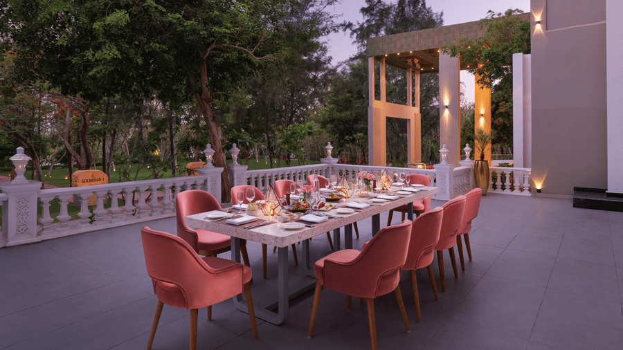 An outdoor dining area at Essentia Luxury Resort & Spa, Udaipur, featuring a table set for dinner.. 